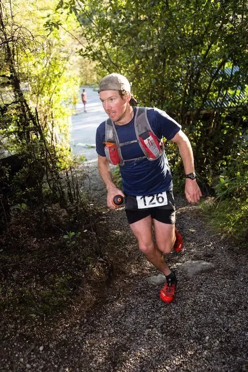A man is running down a trail in the woods.