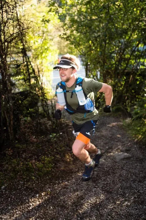 A man is running on a trail in the woods.