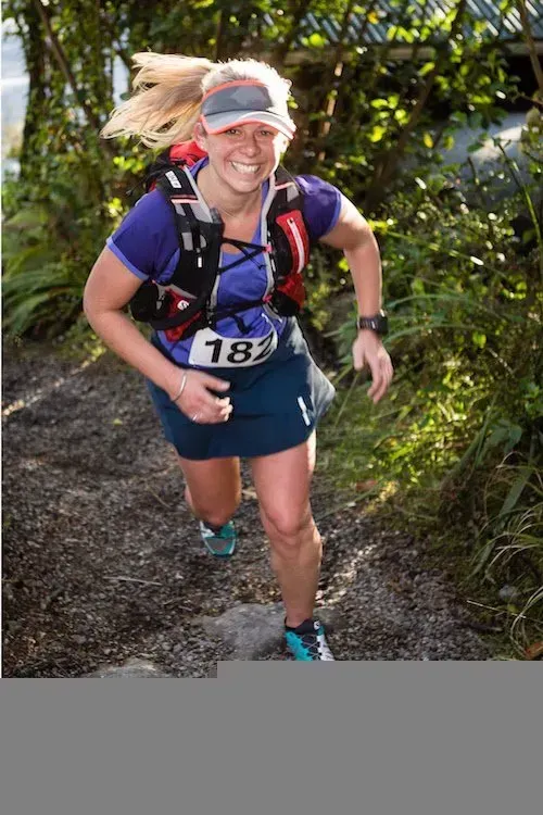 A woman is running on a trail with the number 18 on her shirt.