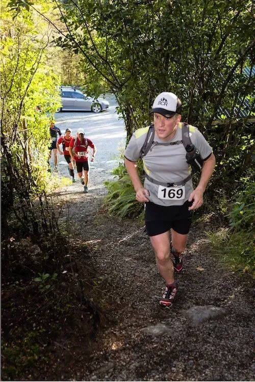 A man with the number 169 on his shirt is running down a trail.