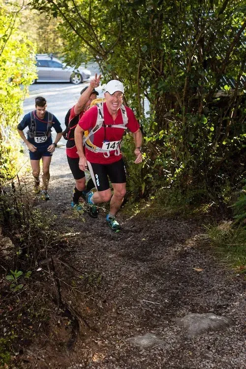 A group of people are running down a dirt path.