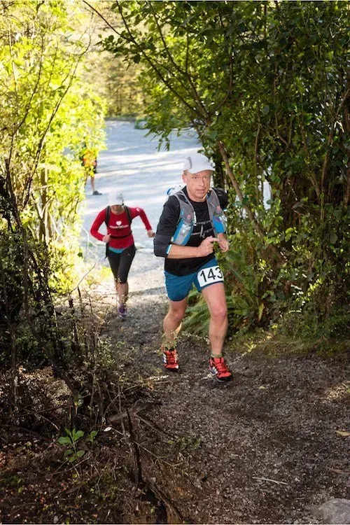 A man and a woman are running up a hill.