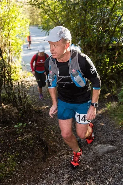 A man is running up a hill wearing a number 14 bib.