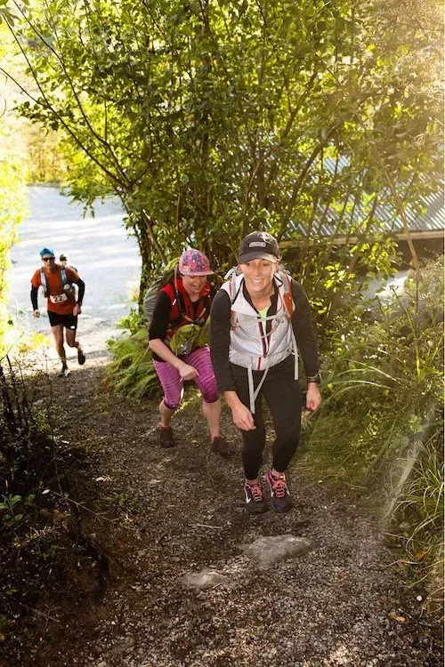 A group of people are walking down a path in the woods.