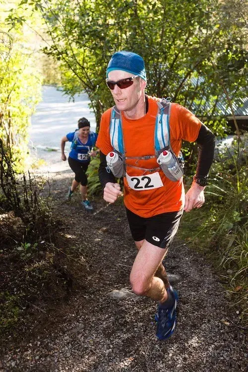 A man is running down a trail with a number 22 on his shirt.