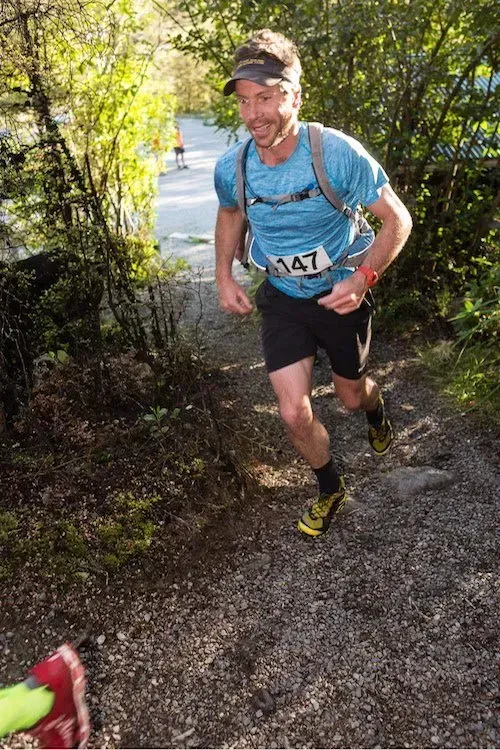 A man is running down a trail in the woods.