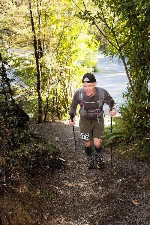 A man is walking up a hill with hiking poles.