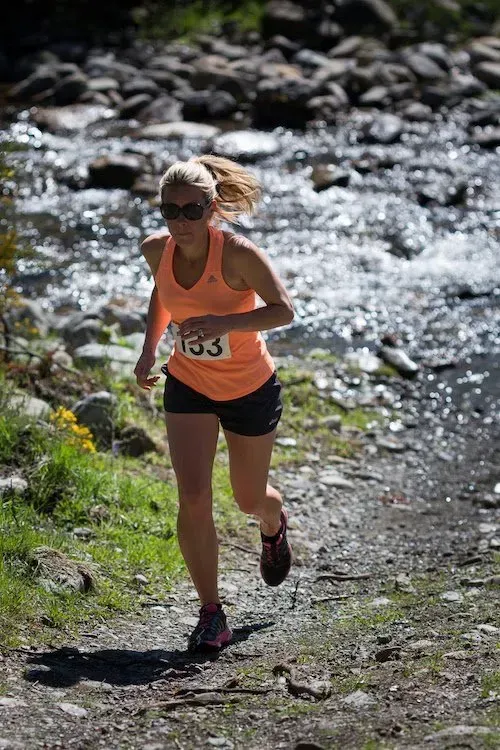 A woman is running on a trail next to a river.