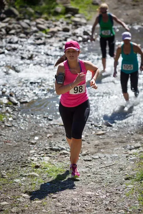 A group of women are running through a stream.