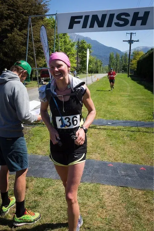 A woman is smiling at the finish line of a race.
