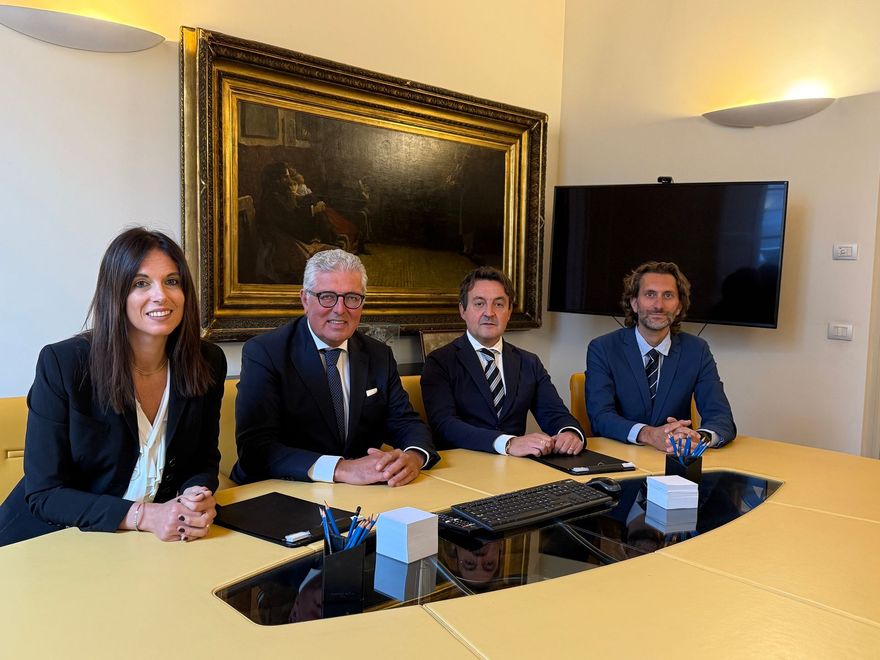 Cinque professionisti in giacca e cravatta posano in una stanza rivestita in legno e dotata di librerie.