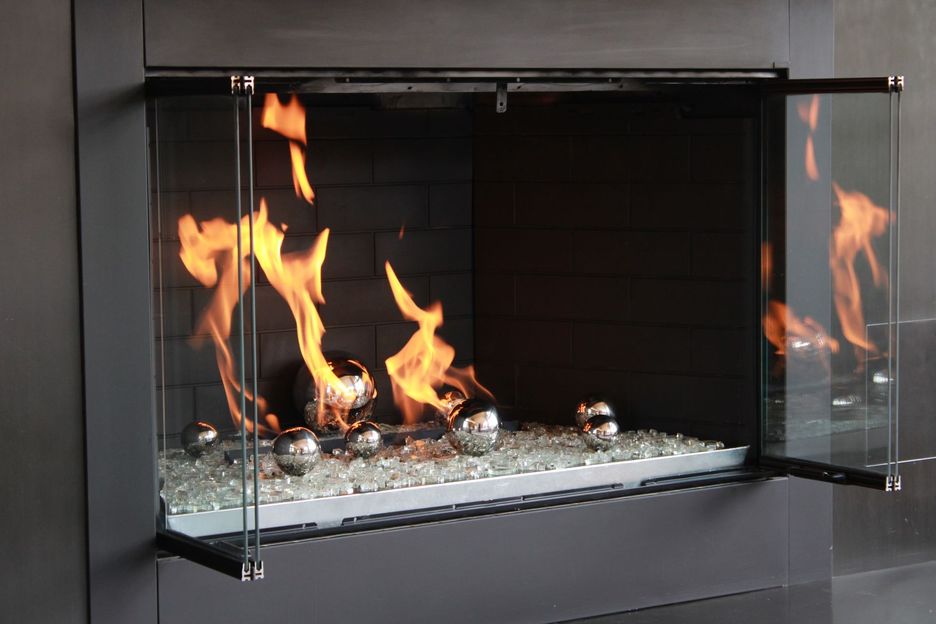 A fireplace with flames coming out of it and a glass door.