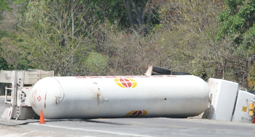 A propane tank is laying on the side of the road.