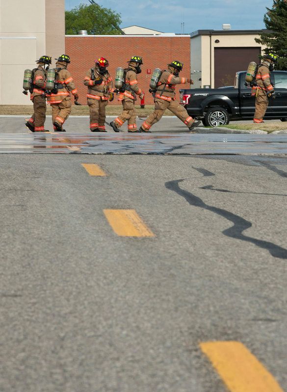 A group of firefighters are walking down a street