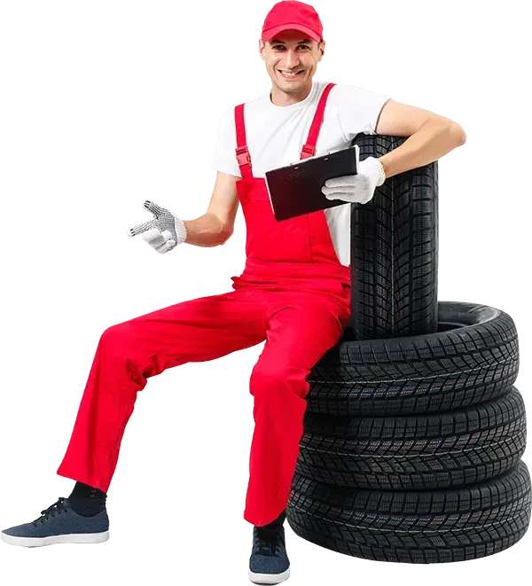 A smiling worker sits on a stack of tires.