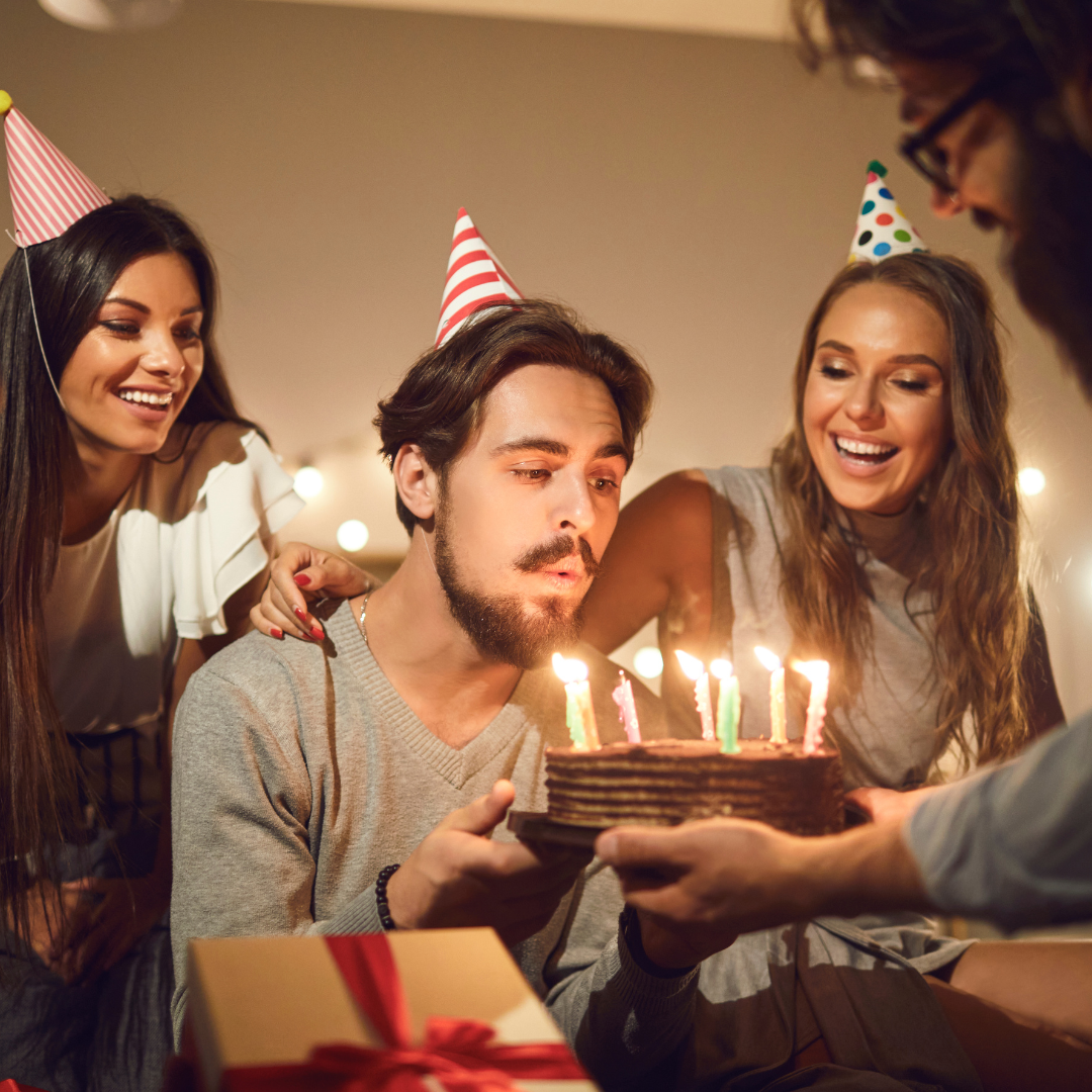 A group of people are celebrating a birthday with a cake and candles.