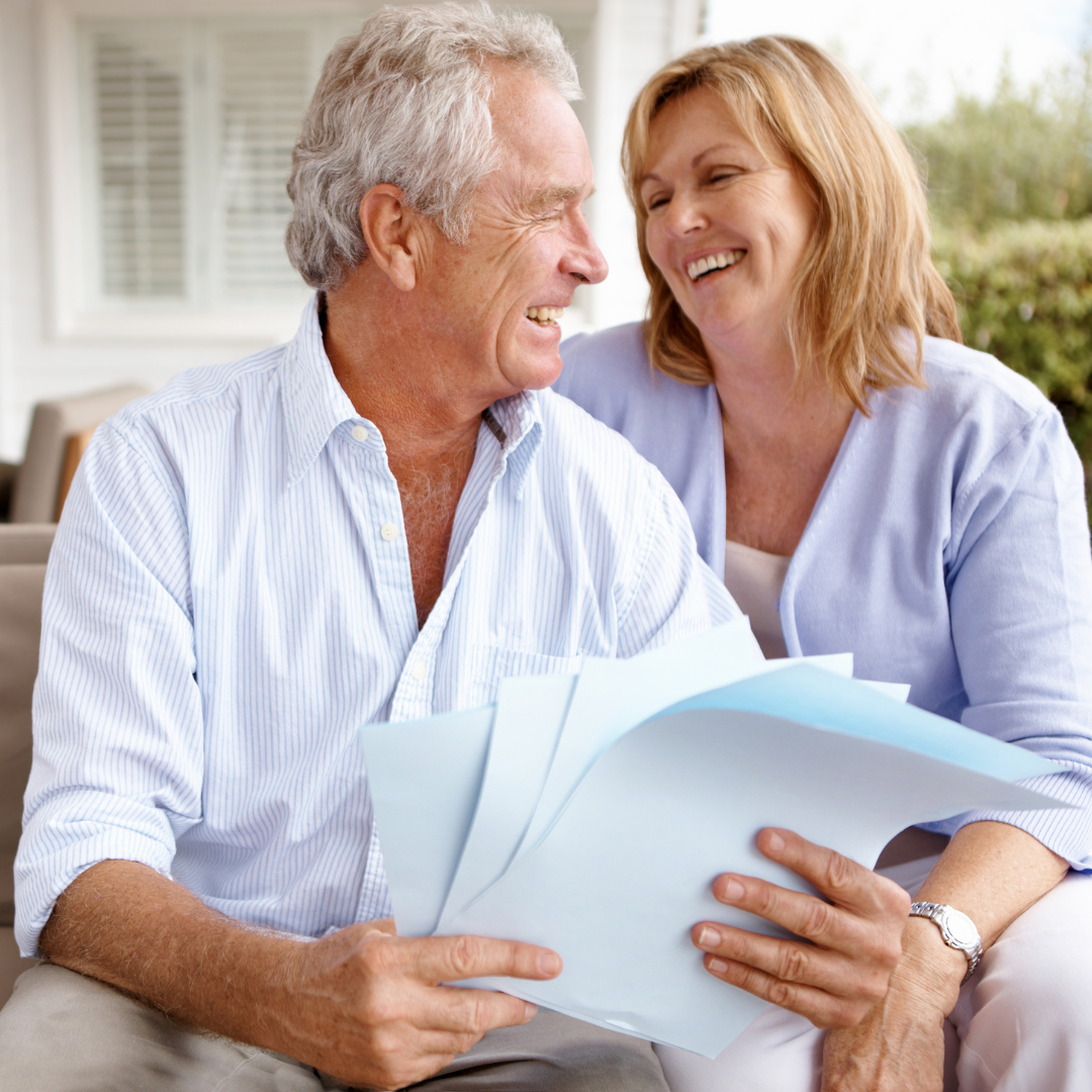 A man and woman are sitting on a couch looking at a piece of paper