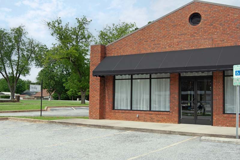 Brick building with black awning and glass windows; handicap parking sign.