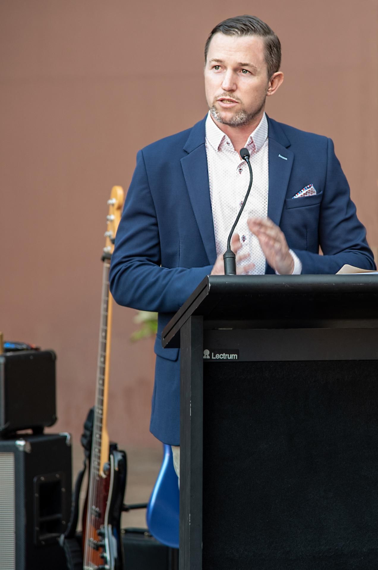 Man in a Blue Blazer Speaks at a Podium Outdoors — Up Here Photography in Rosebery, NT
