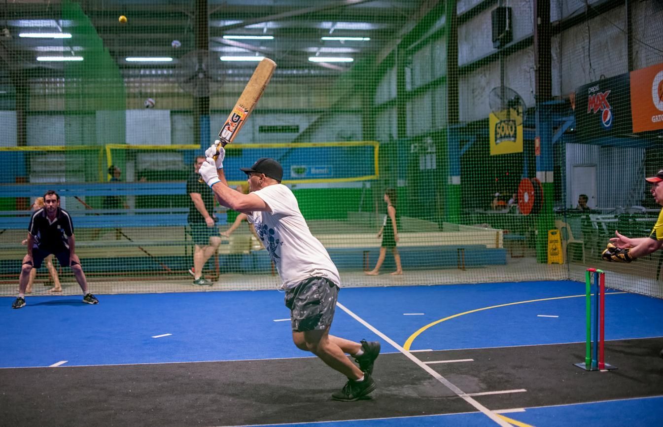 A Man Swings a Bat in front of a Pepsi Sign — Photography in Darwin, NT