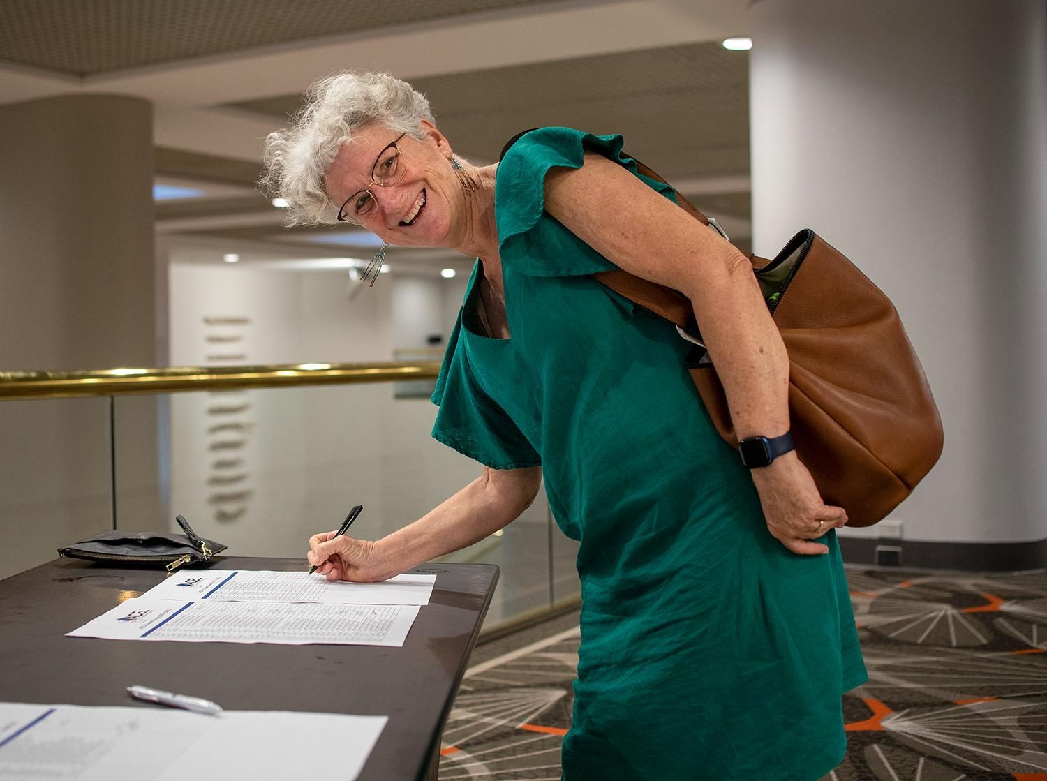 A Woman in a Green Dress is Signing a Form — Photography in Darwin, NT