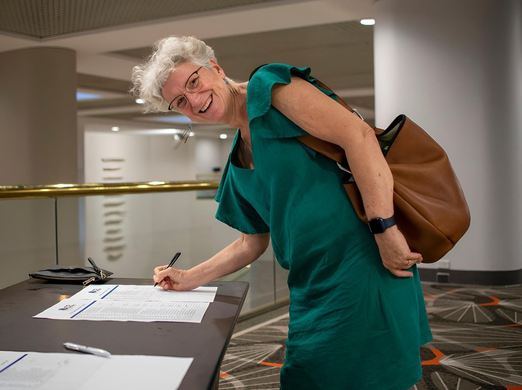 Woman in Green Dress Signs a Document at a Table — Up Here Photography in Palmerston, NT
