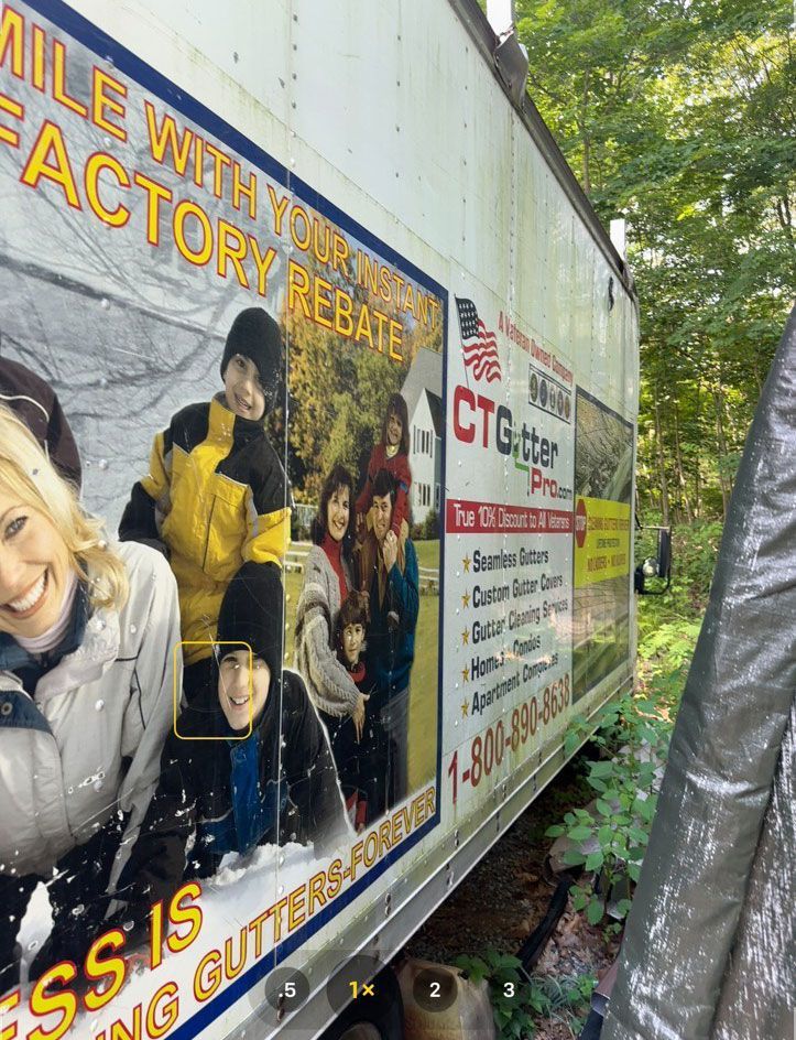 A CT Gutter marketing advertisement on a truck featuring a smiling family, company services, and phone number.