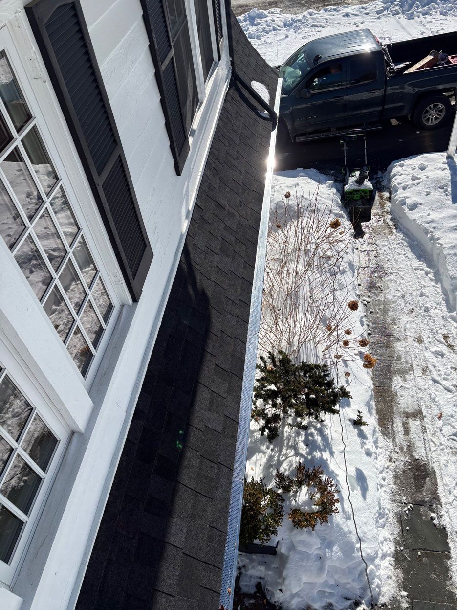 A view from a second-story window looking down at a snow-covered ground with a truck parked in the driveway.