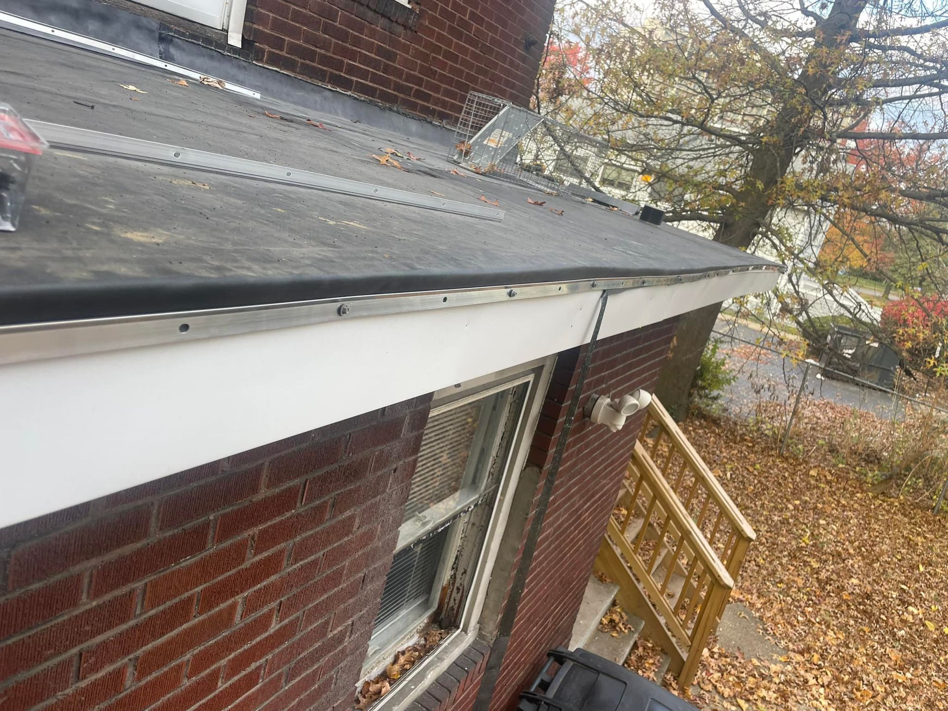 Brick building with a dark roof and white trim. A gutter runs along the roof edge.