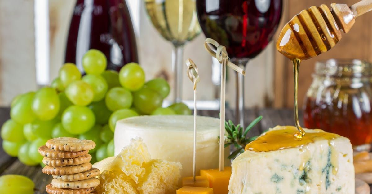 A plate of cheese , crackers , grapes and wine glasses on a table.