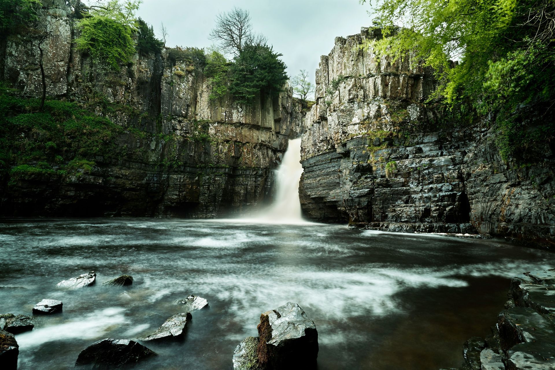 A waterfall in the middle of a river surrounded by trees