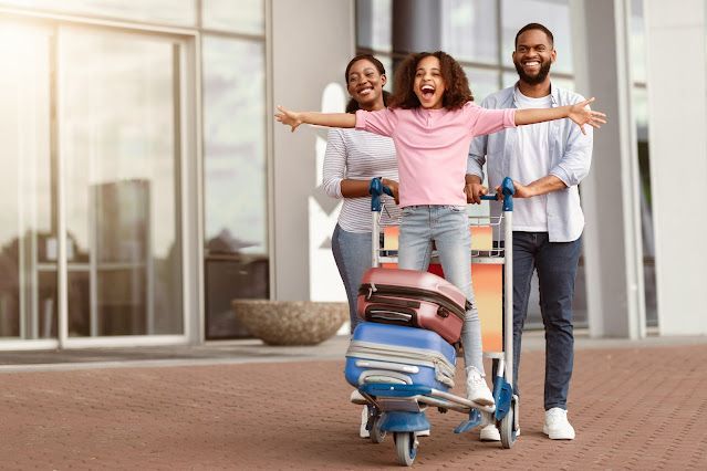 A family is carrying luggage on a cart at the airport.