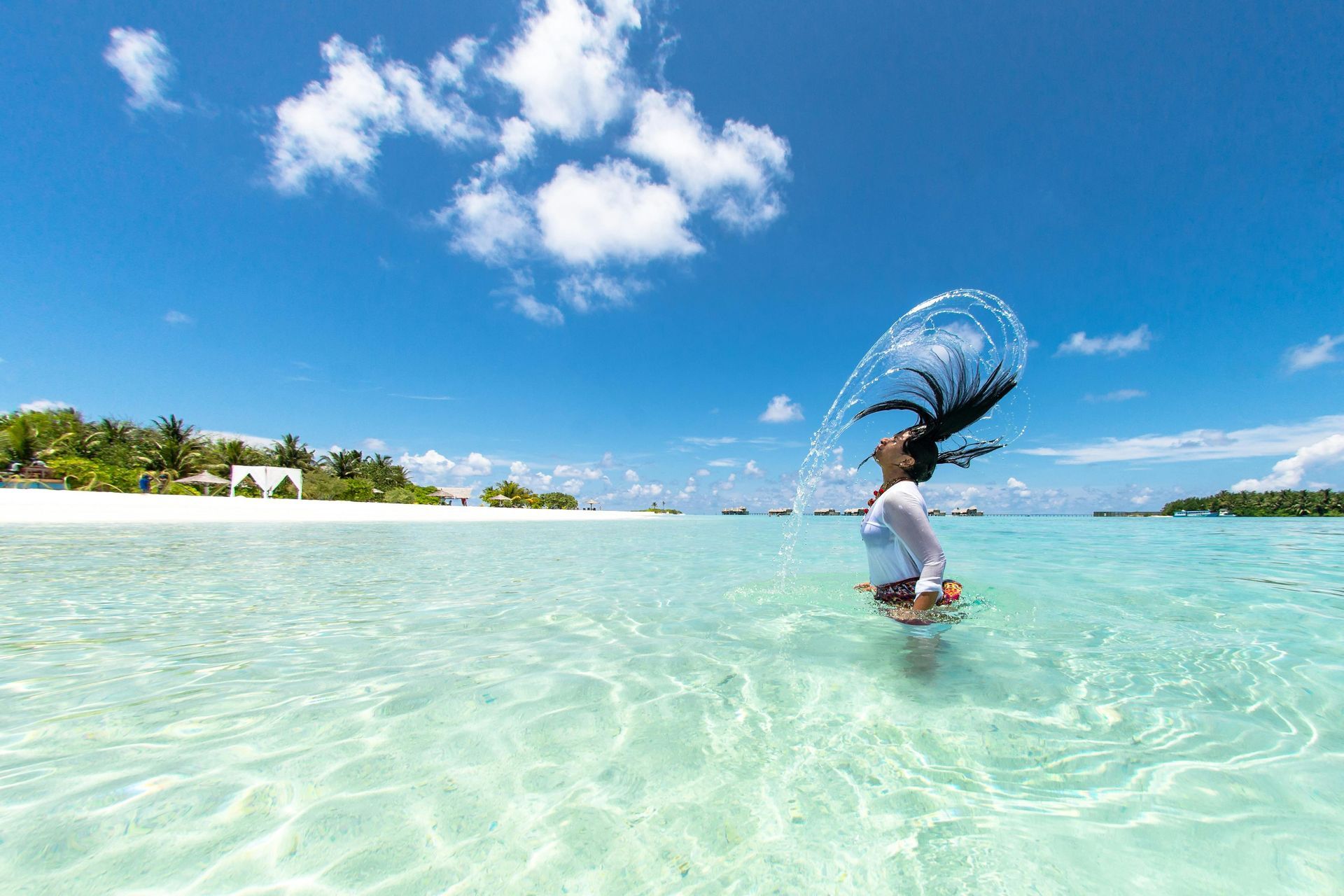 A woman is splashing her hair in the ocean.