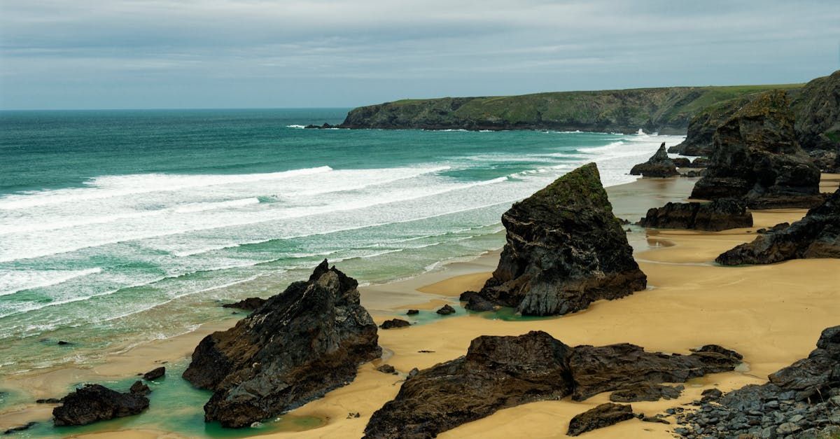 A beach with rocks and waves coming in on a cloudy day