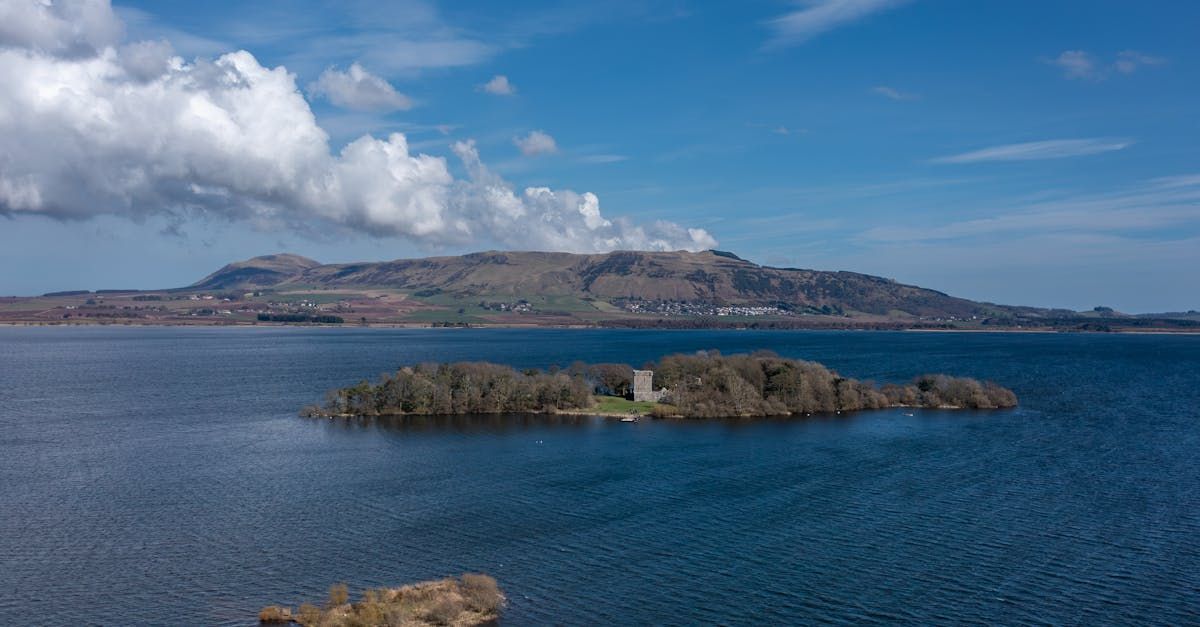 A small island in the middle of a large body of water with mountains in the background.