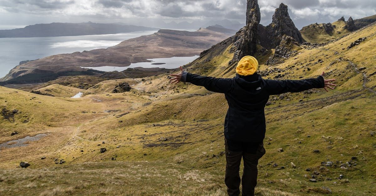 A person is standing on top of a hill with their arms outstretched.