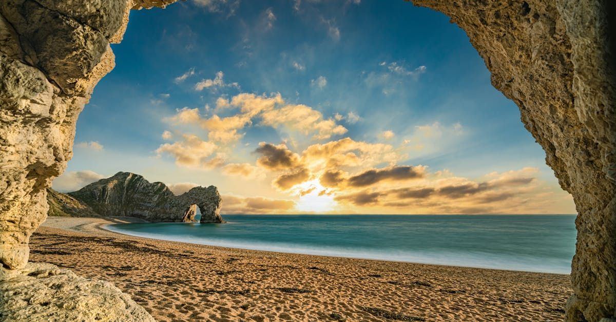 A view of a beach from a cave at sunset.