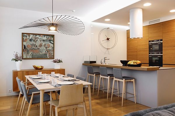Dining and kitchen area: Light wood, modern design, dining table with place settings, kitchen island with bar stools.