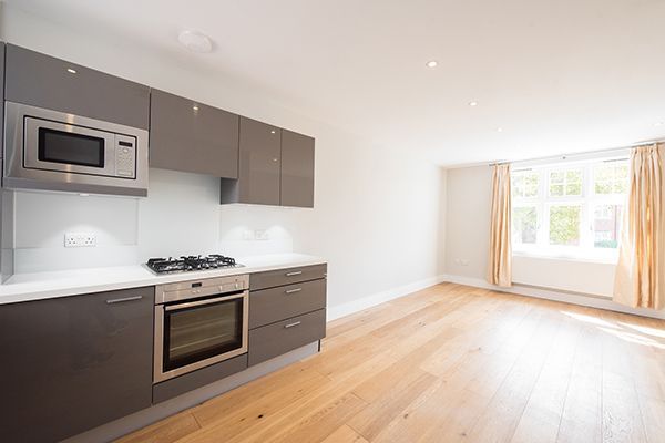 Modern kitchen with gray cabinets, microwave, oven, and hardwood floors.