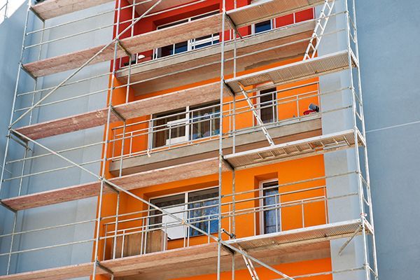 Building facade under renovation with scaffolding; orange and gray paint.