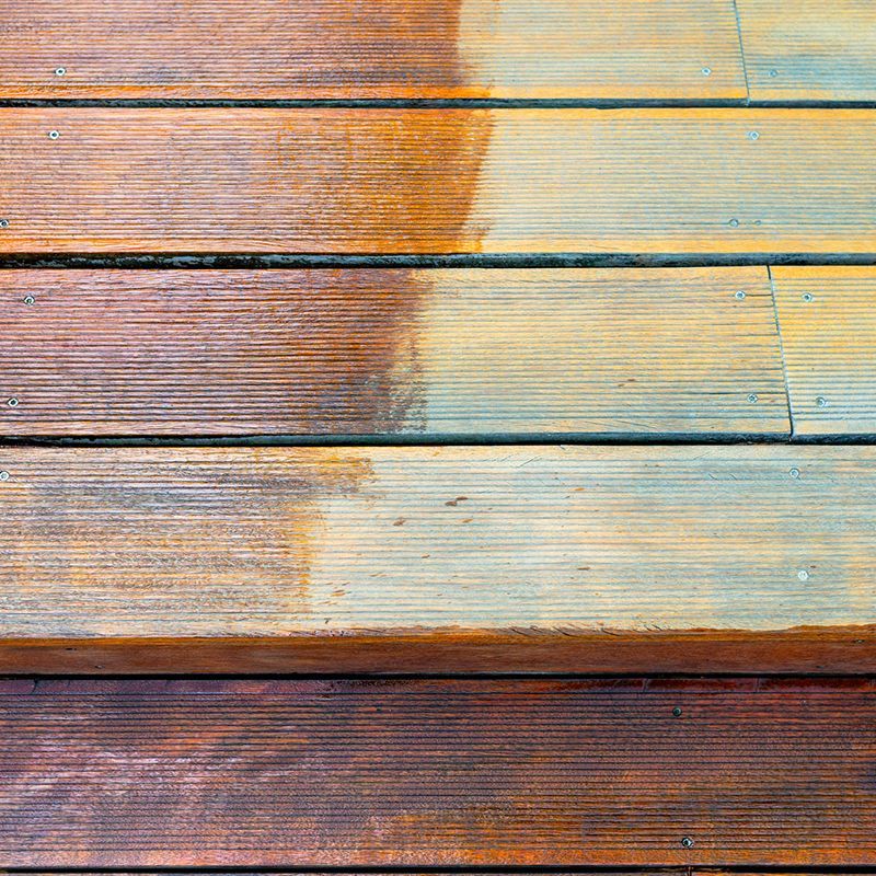 Wooden deck planks partially cleaned; shows contrast between stained and weathered areas.
