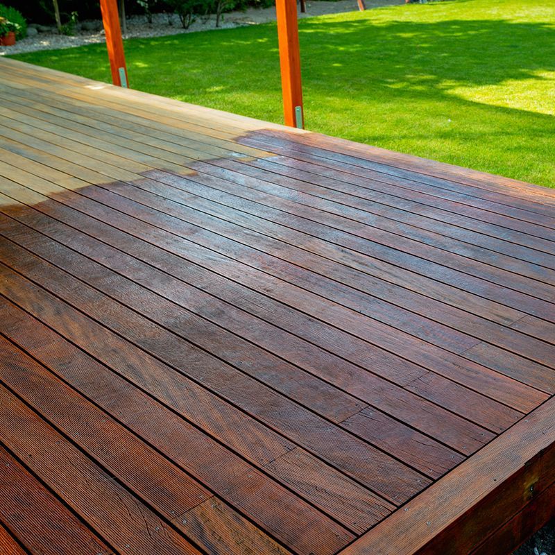 Wooden deck with dark stain, in a sunny yard.