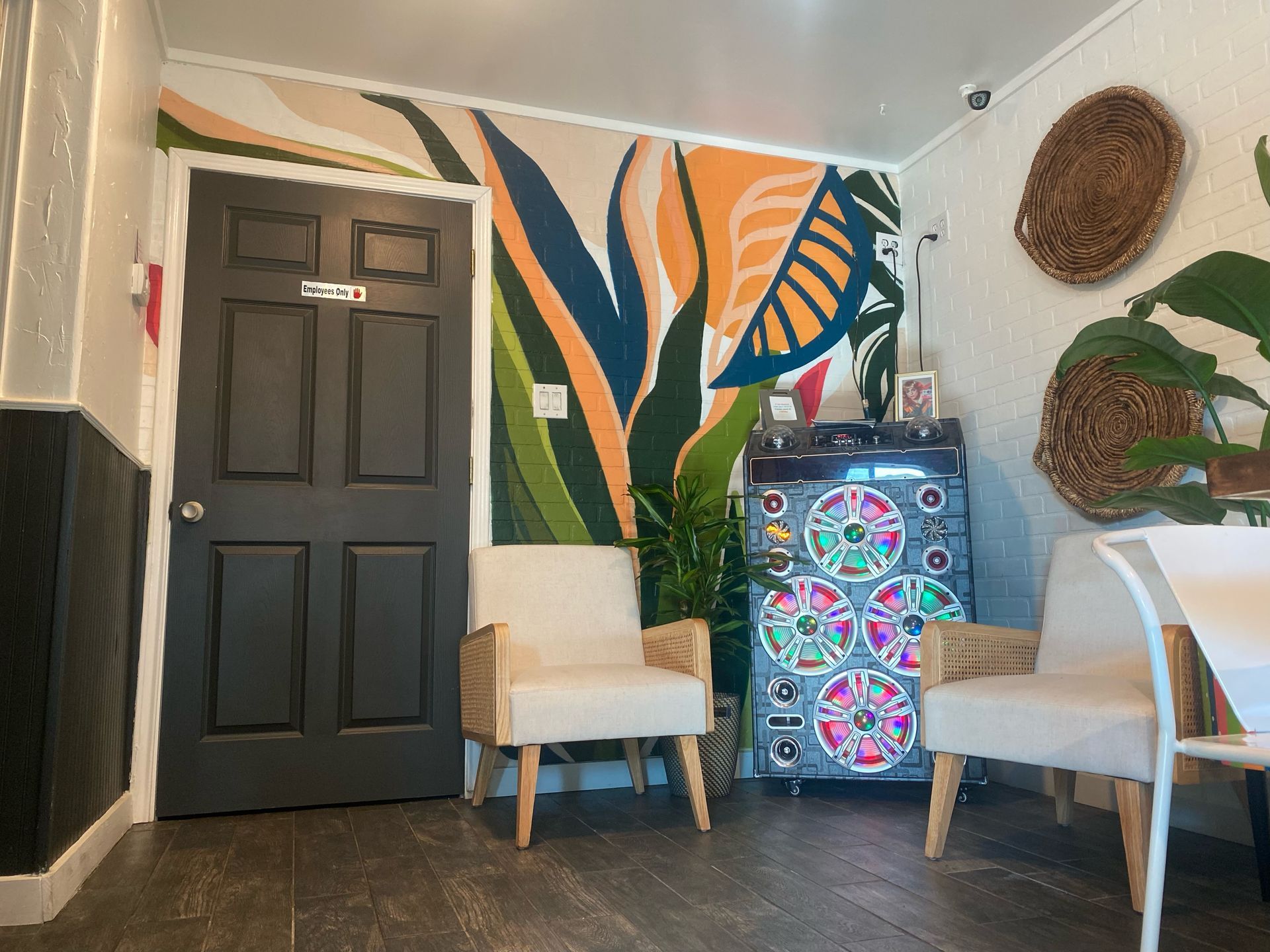 An interior with a black door, two chairs, a colorful mural, and a jukebox.