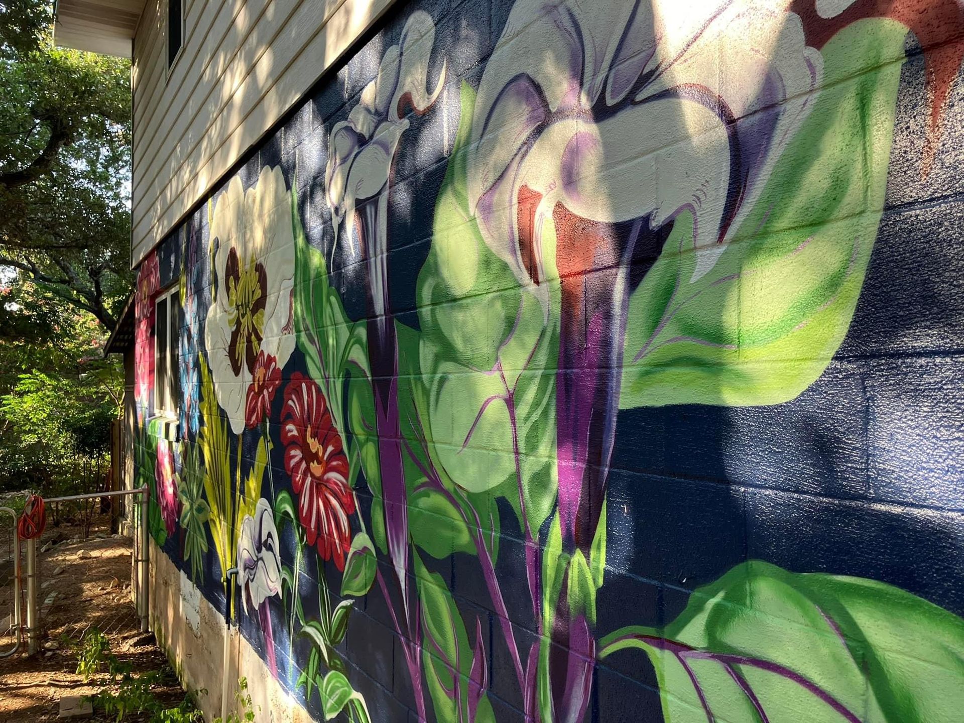 Mural of colorful flowers and foliage painted on a dark blue brick wall.