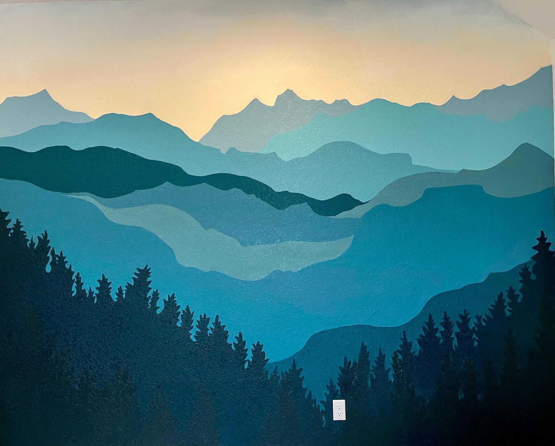 Blue mountain range silhouette mural with pine trees and light sky.