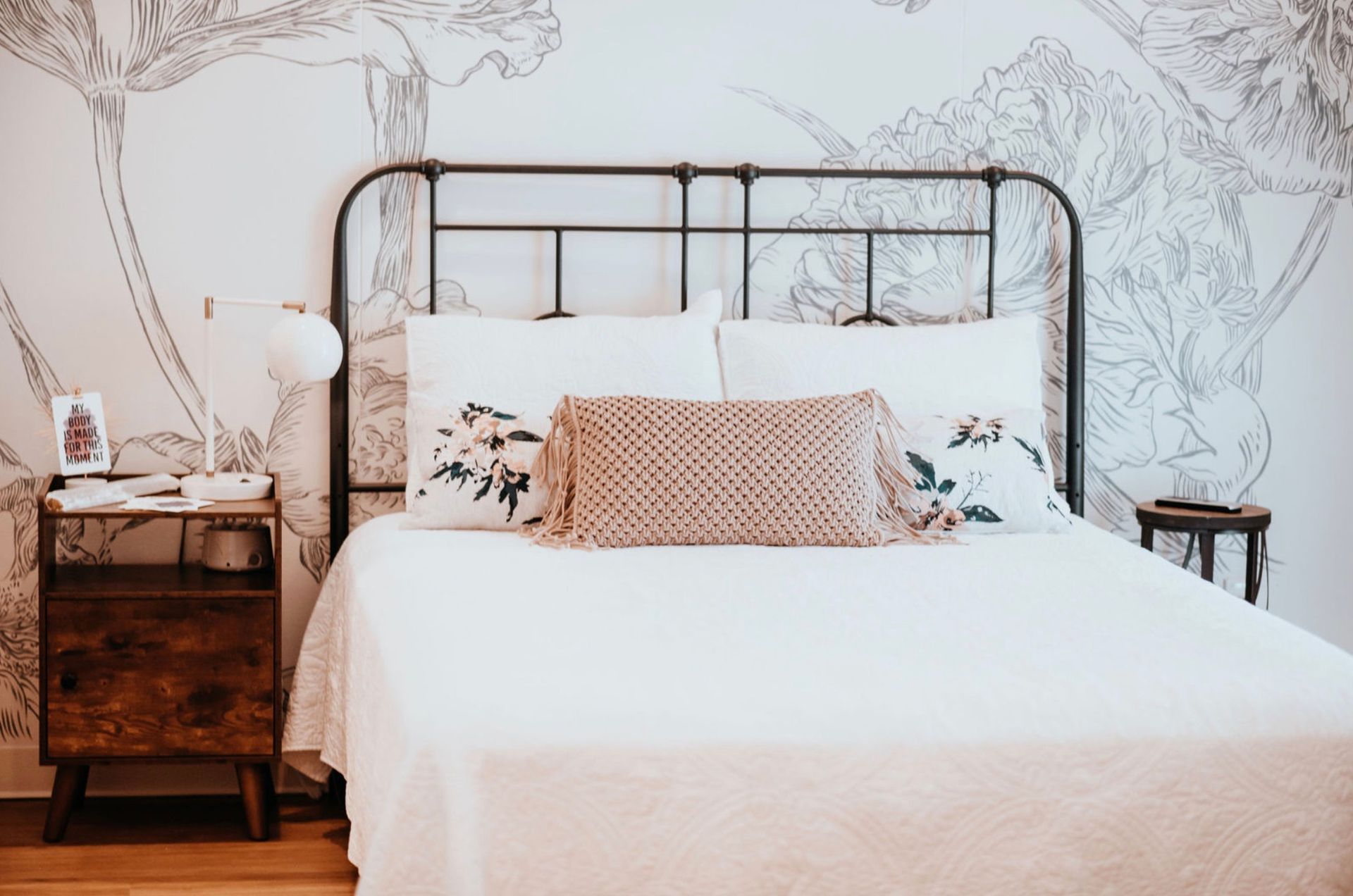 Bedroom with bed, nightstands, floral wallpaper, and neutral decor.