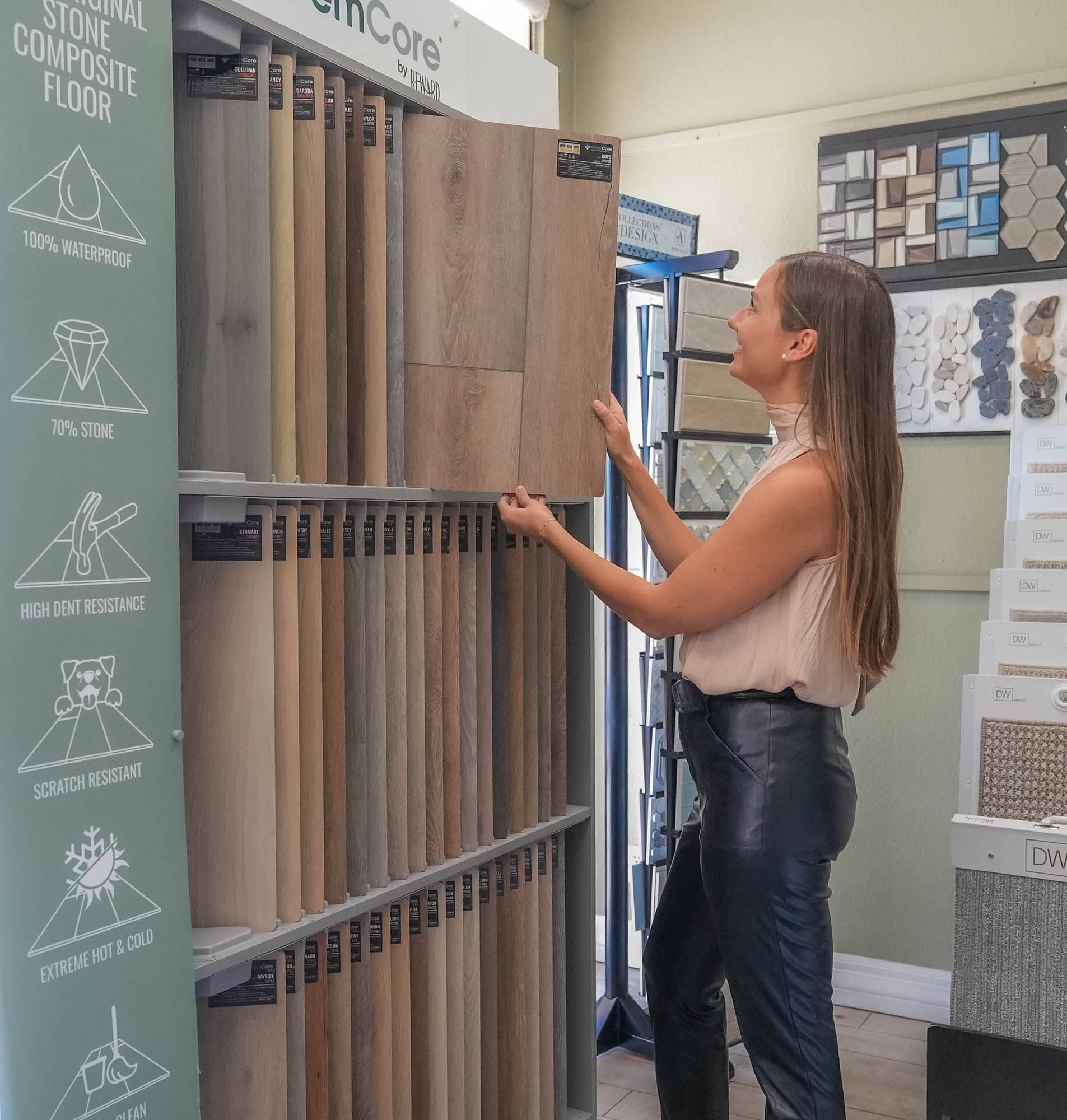 A woman is standing in front of a display of composite flooring