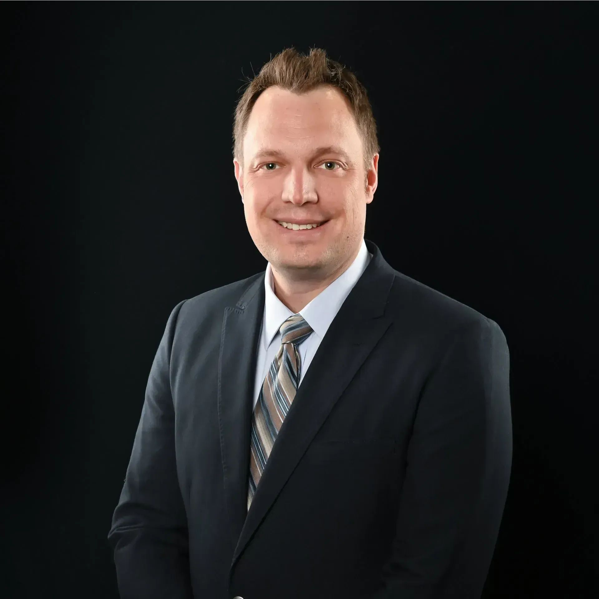 A man in a suit and tie is smiling for the camera.