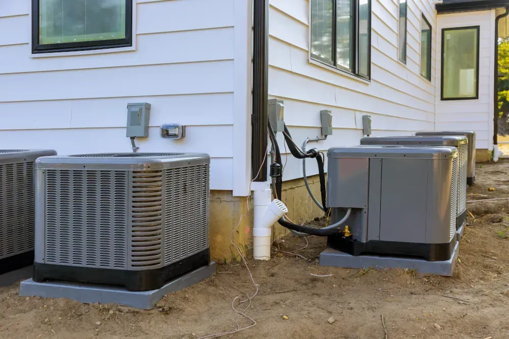 There are two air conditioners on the side of a house.