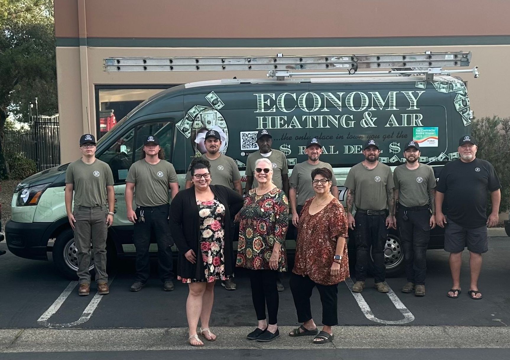 A group of people standing in front of a van that says economy heating and air.
